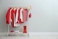 Rack with bright stylish clothes, shoes and accessories near light grey wall indoors, space for text Royalty Free Stock Photo