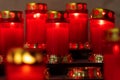 A rack of burning red votive prayer candles in a italian church. Candlelight fire flames in rows are silent religion symbol for Royalty Free Stock Photo