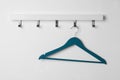 Rack with empty blue clothes hanger on white wall Royalty Free Stock Photo