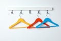 Rack with empty bright clothes hangers on white wall Royalty Free Stock Photo