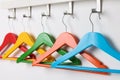 Rack with empty bright clothes hangers on white wall Royalty Free Stock Photo
