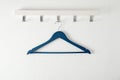 Rack with empty clothes hanger on light wall. Royalty Free Stock Photo