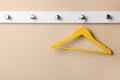Rack with empty yellow clothes hanger on beige wall Royalty Free Stock Photo