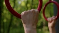 Rack focus close up hand of slender athletic woman takes on gymnastic rings. girl in park is doing workout and go in for