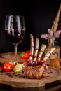 Rack of lamb with grilled vegetables and raspberry sauce. Serving dishes on a wooden board with a glass of red wine