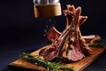 Rack of lamb with rosemary on wooden cutting board over dark background, side view, selective focus Royalty Free Stock Photo