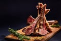 Rack of lamb with rosemary on wooden cutting board over dark background, side view, selective focus Royalty Free Stock Photo