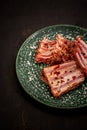 Rack of raw pork spare ribs seasoned with spices on black slate tray with paprika, garlic, textured black background, view from Royalty Free Stock Photo