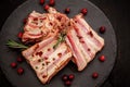 Rack of raw spare pork ribs flavored with spices on a black slate with paprika, bay leaves on the background, top view, close-up Royalty Free Stock Photo