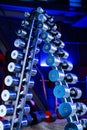 Rack with a set of metal silvery dumbbells in the gym. Shiny dumbbells of different weights and barbell in sports club Royalty Free Stock Photo