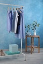 Rack with stylish clothes near light blue wall Royalty Free Stock Photo