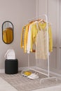 Rack with stylish women`s clothes, backpack and shoes near light wall in dressing room Royalty Free Stock Photo