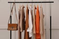 Rack with stylish women`s clothes and bag near light wall Royalty Free Stock Photo