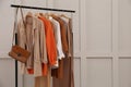 Rack with stylish women`s clothes and bag near light wall. Space for text Royalty Free Stock Photo