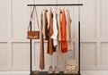 Rack with stylish women`s clothes, shoes and accessories near light wall Royalty Free Stock Photo