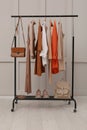 Rack with stylish women`s clothes, shoes and accessories near light wall in room Royalty Free Stock Photo