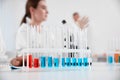 Rack with test tubes on white table and laboratory assistants in room