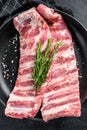 Rack of uncooked raw pork spare ribs seasoned with spices in a pan. Black background. Top view Royalty Free Stock Photo