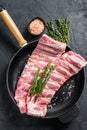 Rack of uncooked raw pork spare ribs seasoned with spices in a pan. Black background. Top view Royalty Free Stock Photo