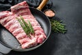 Rack of uncooked raw pork spare ribs seasoned with spices in a pan. Black background. Top view. Copy space Royalty Free Stock Photo