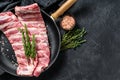 Rack of uncooked raw pork spare ribs seasoned with spices in a pan. Black background. Top view. Copy space Royalty Free Stock Photo