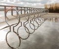 Racks for bikes in perspective. Circular public bicycle racks in a park with reflection in the water after rain