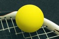 Racquetball on racket strings. Yellow frontenis ball laying on r