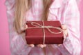 Rad giftbox in female hands in pink background Royalty Free Stock Photo