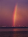 Radiant beam of rainbow over the sea and coast in a dark purplish-red sky, summer night by thunderstorm