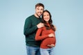 Expectant couple smiling, man embracing pregnant partner