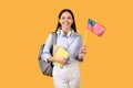 Smiling female student with American flag, headphones and notebooks Royalty Free Stock Photo