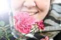 A radiant pink flower held by a smiling happy woman who appears to be cold. Royalty Free Stock Photo