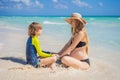 A radiant pregnant mother and her excited son share a tender moment on a serene, snow-white beach, celebrating