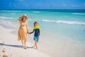 A radiant pregnant mother and her excited son share a tender moment on a serene, snow-white beach, celebrating