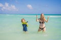 A radiant pregnant mother and her excited son share a tender moment on a serene, snow-white beach, celebrating