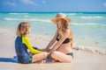 A radiant pregnant mother and her excited son share a tender moment on a serene, snow-white beach, celebrating