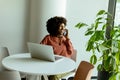 Radiant Woman Engaging in a Phone Conversation While Working at a Bright Cafe Royalty Free Stock Photo