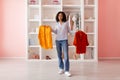 Happy woman with two colorful shirts in closet