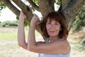 Radiant young aging woman touching a tree with sensuality Royalty Free Stock Photo