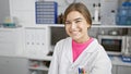 Radiant young hispanic woman, a confident scientist, joyfully smiling amidst her laboratory work, a beautiful expression of