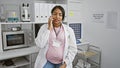 Radiant young pregnant woman scientist confidently having smiling conversation on smartphone while sitting in a bustling