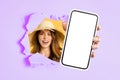 Radiant young woman in a straw hat smiling through a torn purple and yellow paper Royalty Free Stock Photo