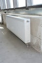 Radiator heating with thermostat in the unfinished modern empty room.