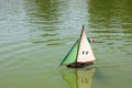 Radio-controlled yacht model with white and green sail and Italian flag.