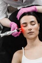 Radio frequency lifting with red light for young woman close-up. Dermatologist is doing radio frequency RF skin Royalty Free Stock Photo