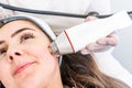 Radio frequency microneedling machine handpiece on the cheek of a woman`s face during a beauty skin tightening treatment Royalty Free Stock Photo