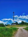 A radio mast on a hill surrounded by trees and a meadow. Cell phone tower and remote station receiver transmitter. Royalty Free Stock Photo