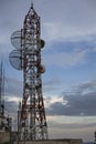 Radio mast supporting four parabolic antennas is kept on the roof of a house. In the nearby houses cable-stayed towers holding sma Royalty Free Stock Photo