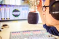 Radio moderator is sitting in a modern broadcasting studio and talking into the microphone