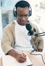 Radio, podcast and black man in office writing notes for advice, questions or feedback while live streaming. Speech